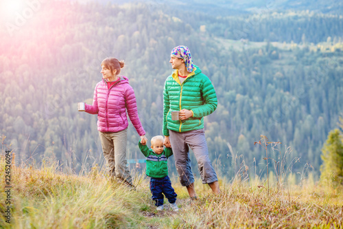 Family, childhood, fatherhood, leisure and people concept - happy father, mother and little toddler son playing and having fun outdoors over nature mountains autunmn background. photo