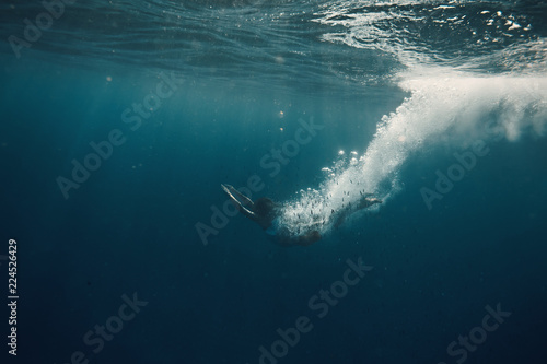 Underwater swimmer in sea with air jet bubbles tail against dark water background