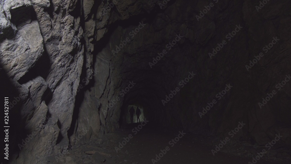 view deep cave with figures of two people with lanterns