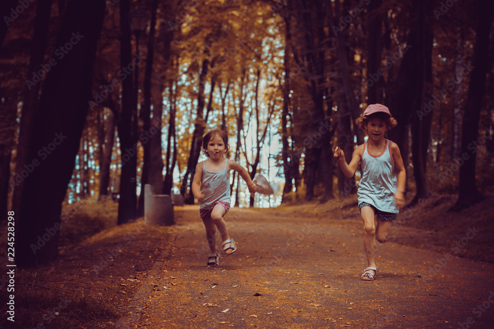 Fototapeta premium Two girls are running around the park, who is first