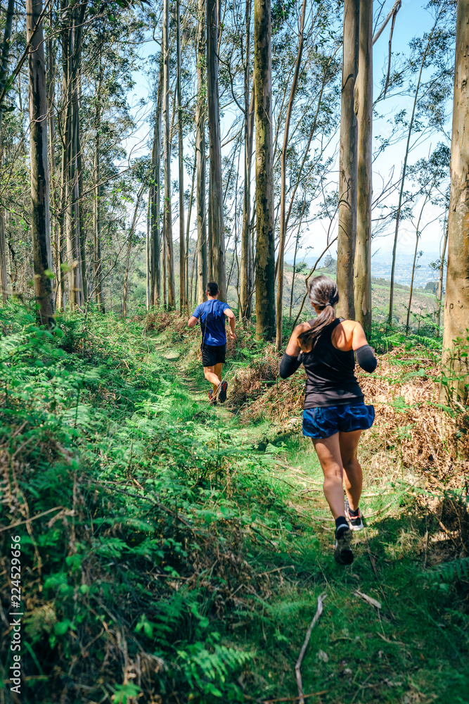 Young woman and man participating in a trail race through the forest