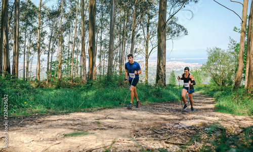Young woman and man participating in a trail race through the forest © David Pereiras