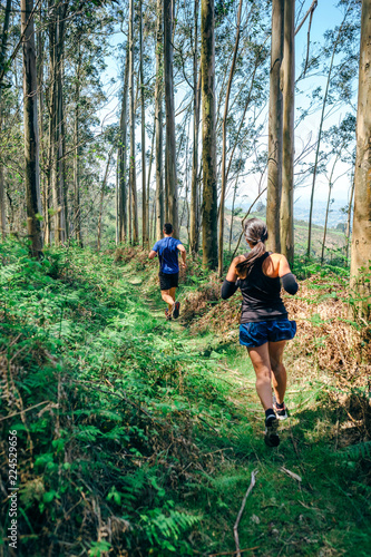 Young woman and man participating in a trail race through the forest