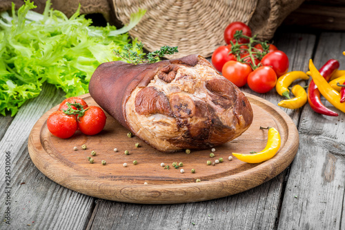 Photography Smoked ham hock with herbs and spices on wooden plate.