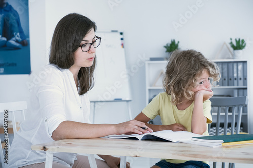 Naughty boy doing homework with mother after classes