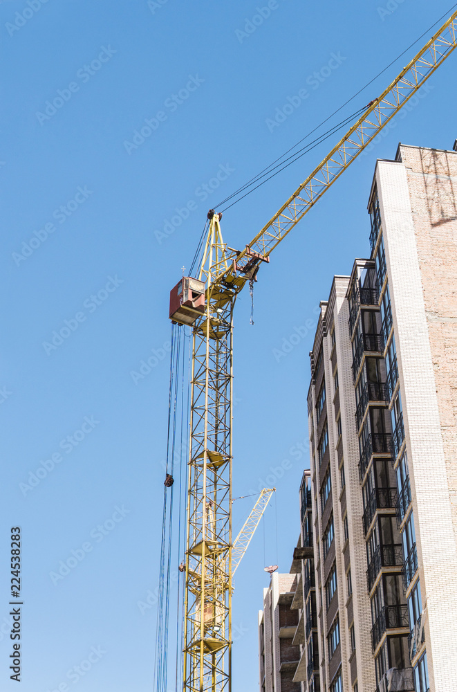 Construction of a high-rise building with a crane. Building construction using formwork. Cranes and buildings against the blue sky.