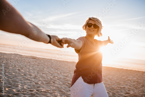 Принти на полотні Smiling woman walking with her girlfriend along a sandy beach