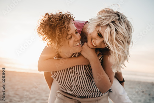 Картината върху платно Laughing lesbian couple having fun together at the beach