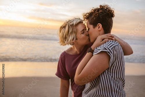 Obraz na plátně Loving young lesbian couple kissing on a beach at sunset