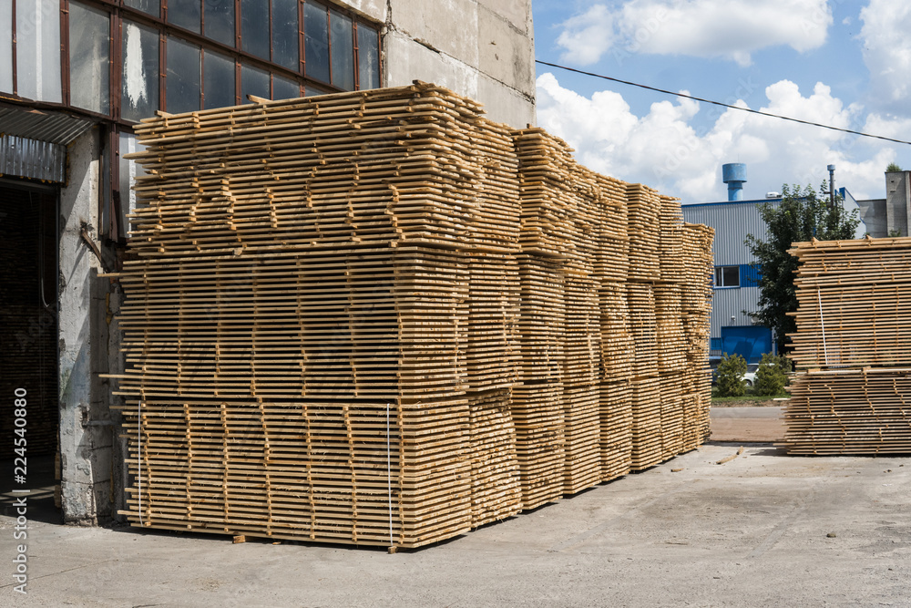 Piles of wooden boards in the sawmill, planking. Warehouse for sawing boards on a sawmill outdoors. Wood timber stack of wooden blanks construction material. Industry. Piles of wooden boards in the sawmill, planking. Warehouse for sawing boards on a sawmill outdoors. Wood timber stack of wooden blanks construction material. Industry.