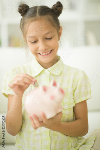 Portrait of cute little girl with a piggy bank