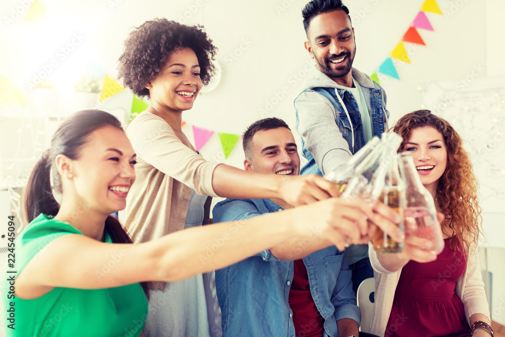 Obraz premium corporate, celebration and holidays concept - happy team clinking bottles with non-alcoholic drinks at office party