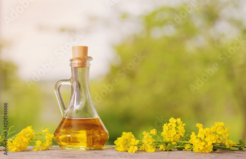rapeseed oil (canola) and rape flowers on wooden table