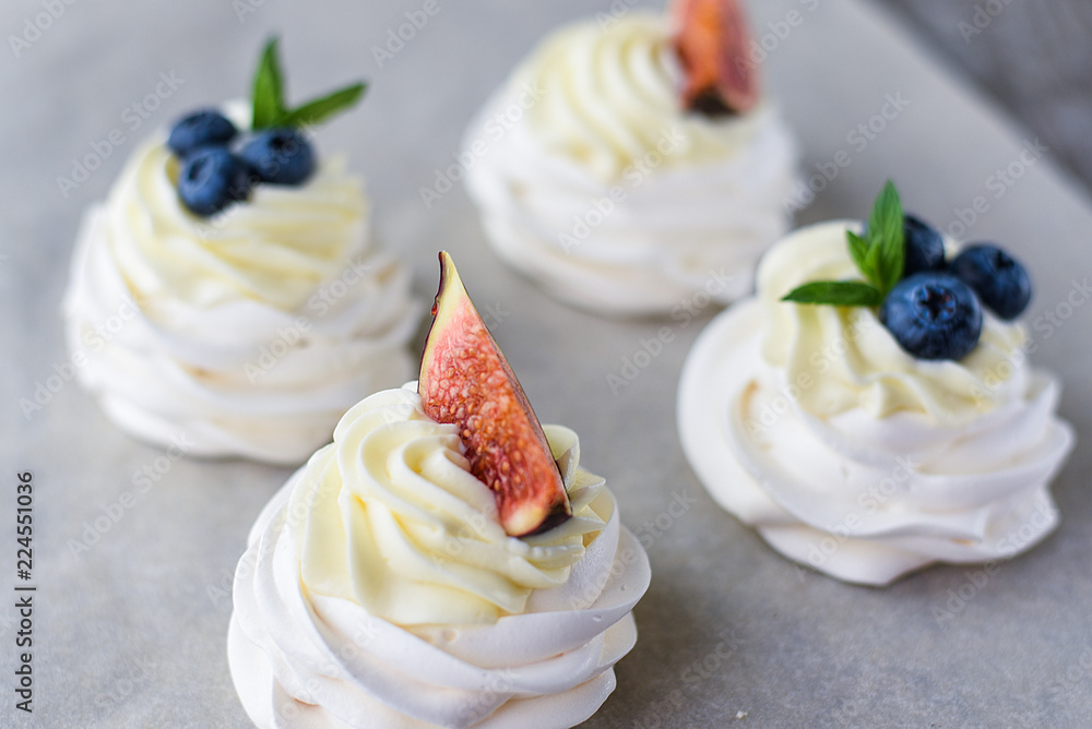 Pavlova meringue cake with figs, blueberries and mint leaves on a wooden background.