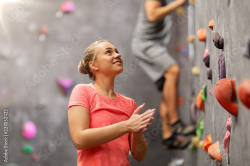 fitness, extreme sport and healthy lifestyle concept - young man and woman bouldering on a rock climbing wall at indoor gym photo