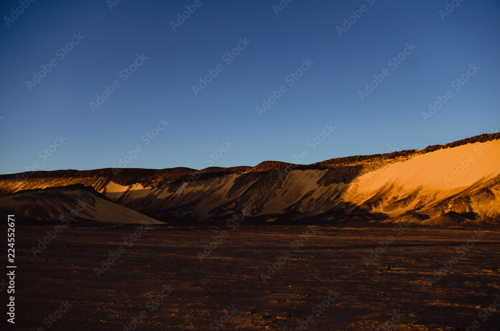 Sunset on the black desert, Black dunes, blue sky Sunset on the black desert, Black dunes, blue sky