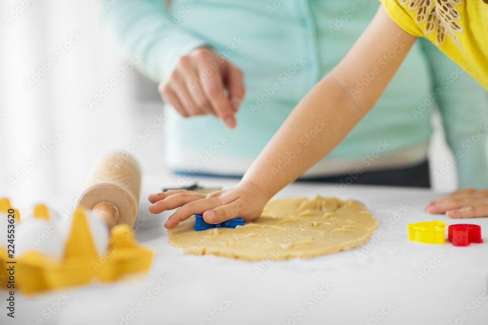 family, cooking and people concept - mother and little daughter with molds making cookies from dough at home kitchen family, cooking and people concept - mother and little daughter with molds making cookies from dough at home kitchen