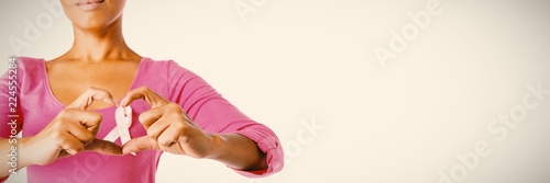Women wearing pink shirt making heart with their fingers around
