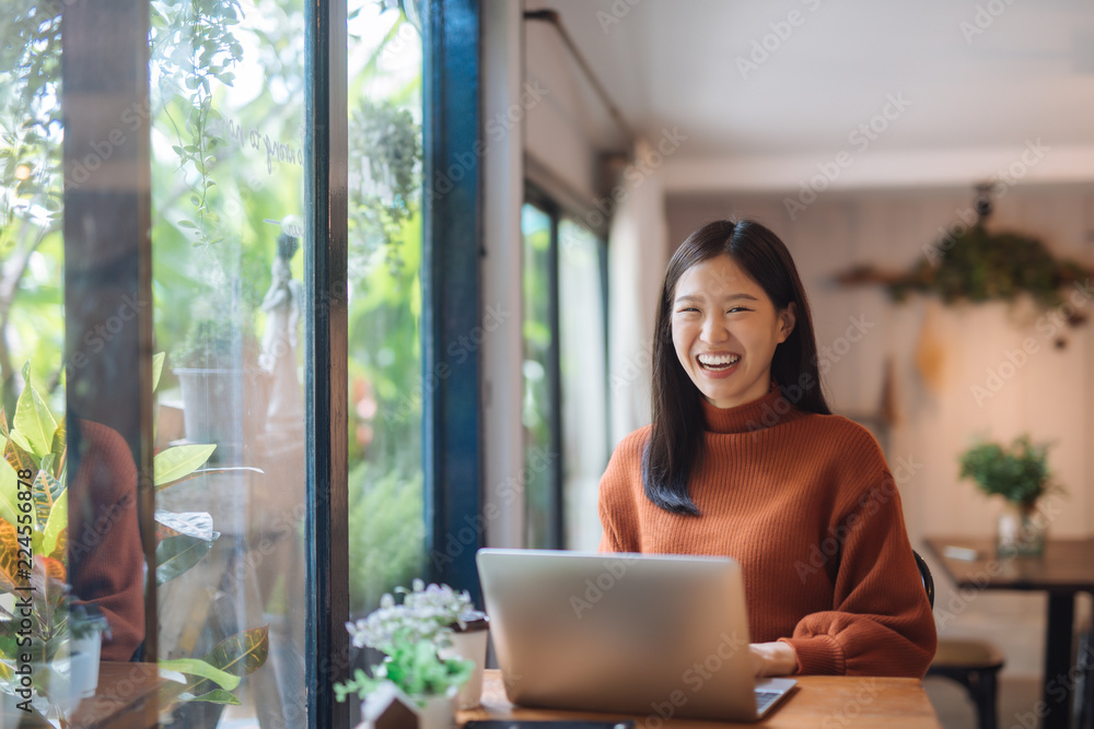 Happy young Asian girl working at a coffee shop with a laptop Happy young Asian girl working at a coffee shop with a laptop
