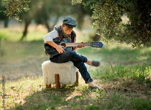 Cute little boy is playing guitar in the park