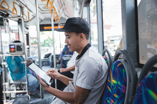 Man traveling by bus and using a tablet 