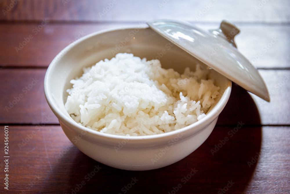 Cooked jasmine rice in a bowl on wooden dining table. Cooked jasmine rice in a bowl on wooden dining table.