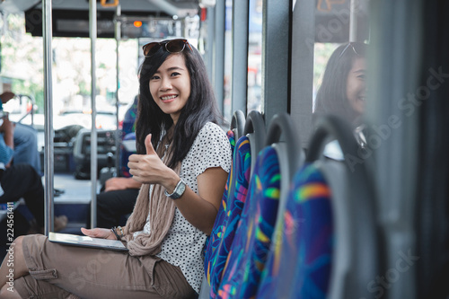 woman using digital tablet on the bus looking camera with thumb 