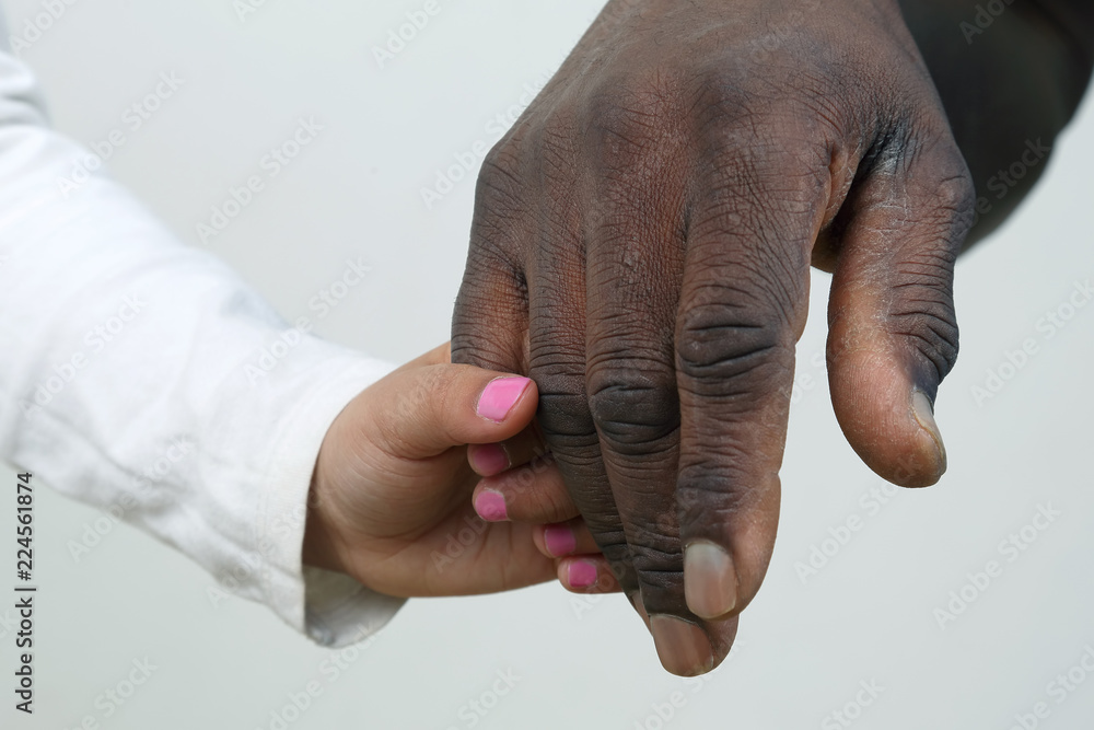 Obraz premium the child holding the hand of a dark-skinned father