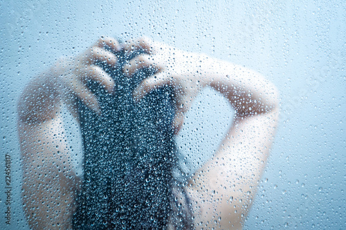 Billede på lærred Women showering in the shower room close up with a water drop on glass door