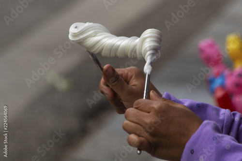 Canvas-taulu Close-up of woman twisting taffy-like confection on metal chopsticks