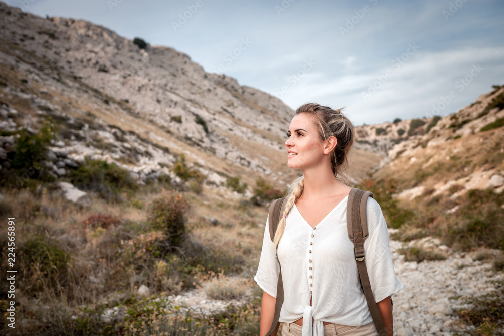 Naklejka premium Beautiful tourist girl on hiking trail in mountain looking at landscape