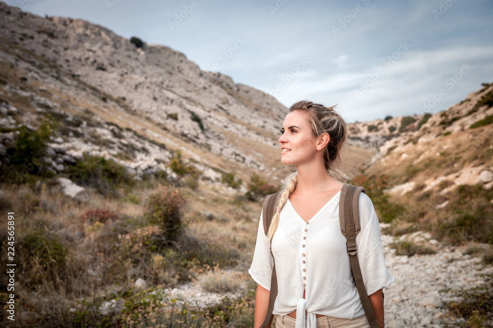 Beautiful tourist girl on hiking trail in mountain looking at landscape