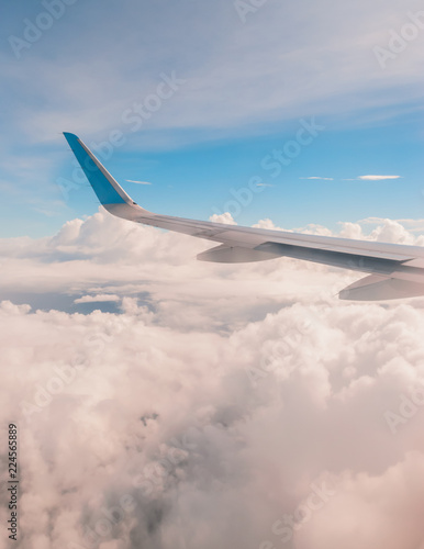 Aerial view of a plane's wing, blue sky and cotton clouds