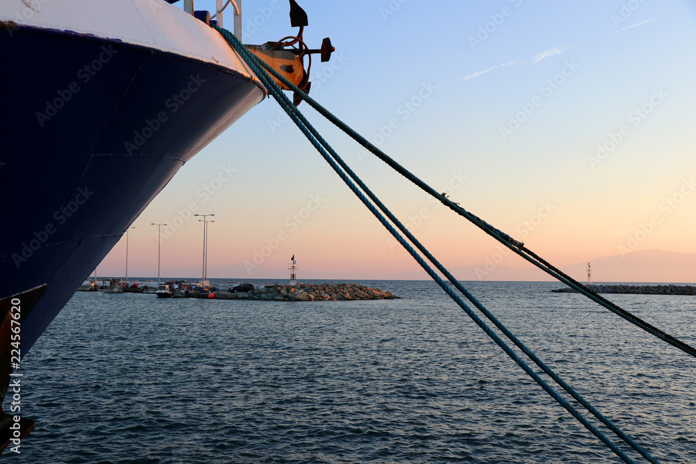Nautical rope moored on the port. Lighthouse background in sunset. 