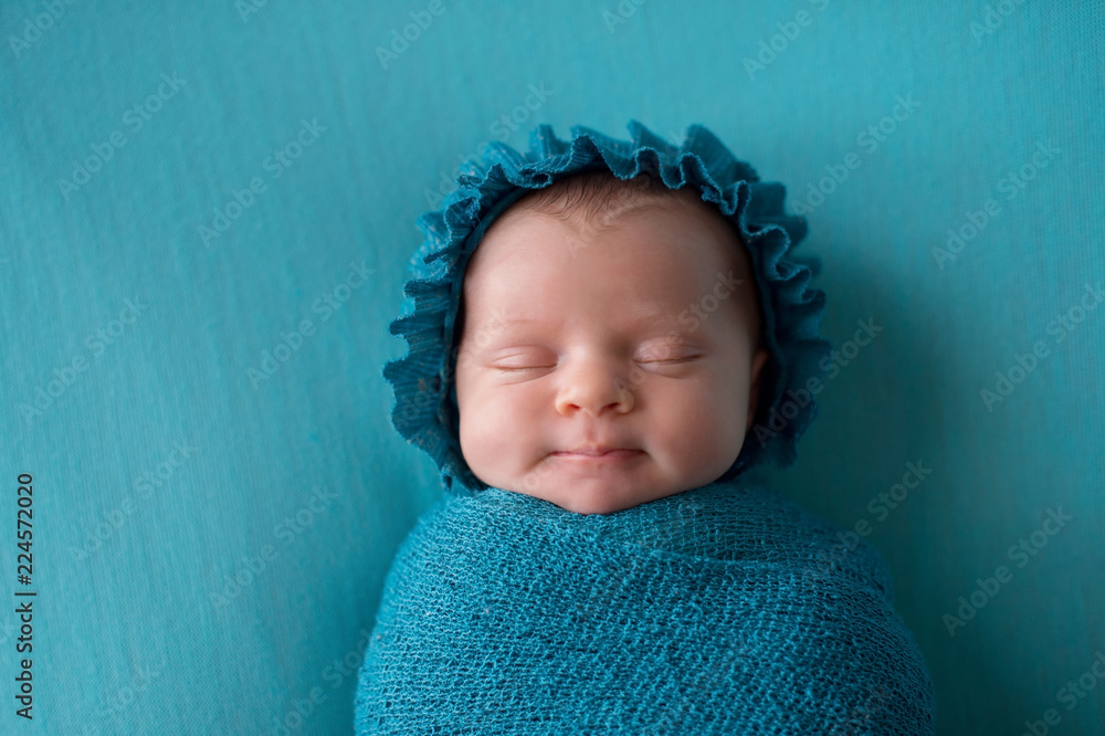 Smiling Newborn Baby Girl Wearing a Turquoise Blue Bonnet - obrazy, fototapety, plakaty 
