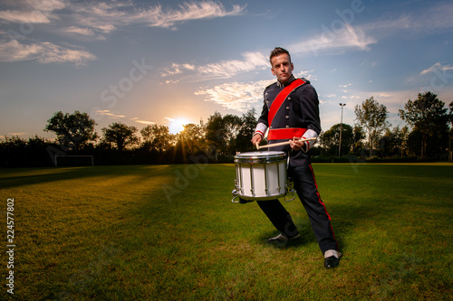 Quadro em tela Cool portrait of musician in uniform with atmospheric light on a green grass fie