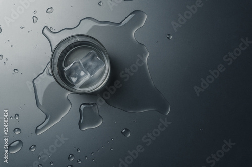 Top view of a glass of water with ice cubes on the wet table