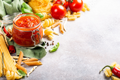 Food background with ingredients for italian healthy homemade classic spicy tomato pasta or pizza sauce with assorted pasta, pine nuts and basil. Copy space.