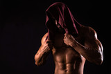 Muscular man is showing his torso with towel on the head