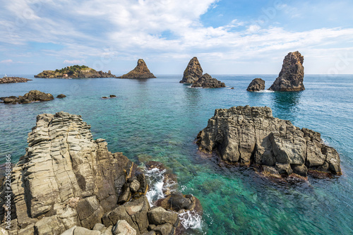 Bild auf Leinwand View on the rocky islands in Aci Trezza, Sicily, Italy, with the Islands of the Cyclops in the background