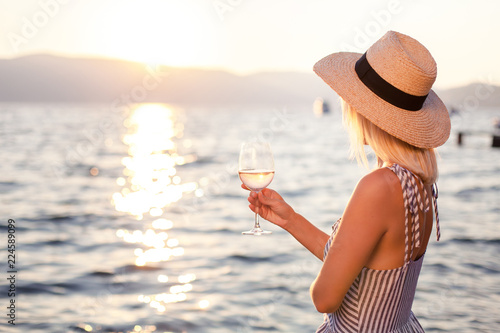 Canvas Print Woman holds wineglass at background of sunset sea or ocean