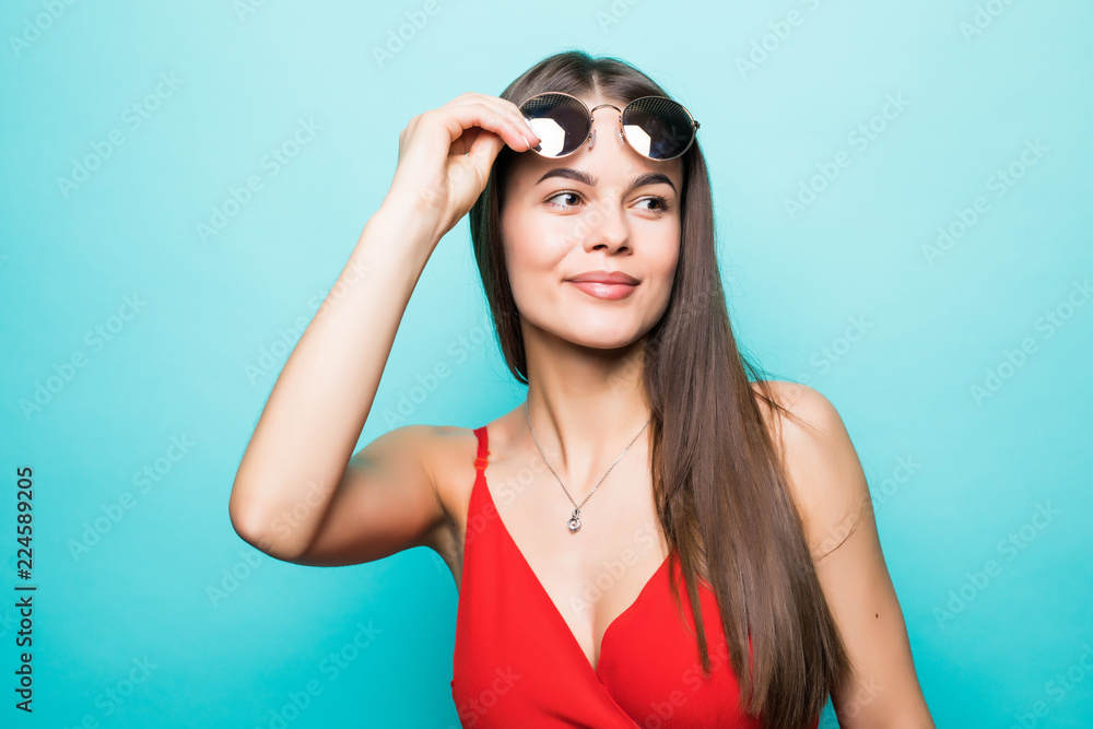 Portrait of a beautiful young girl in sunglasses on a blue background