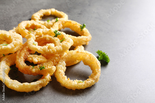 Homemade crunchy fried onion rings on color table, closeup. Space for text