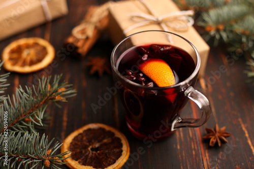 Mulled wine, a gift and spices on the table next to the tree. The concept of Christmas and New Year, decor.