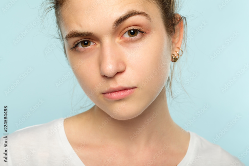 emotion face. suspicious thoughtful dubious distrustful woman raising a brow. young beautiful brown haired girl portrait on blue background. emotion face. suspicious thoughtful dubious distrustful woman raising a brow. young beautiful brown haired girl portrait on blue background.