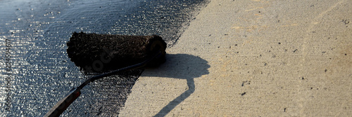 Roofer worker painting black coal tar or bitumen