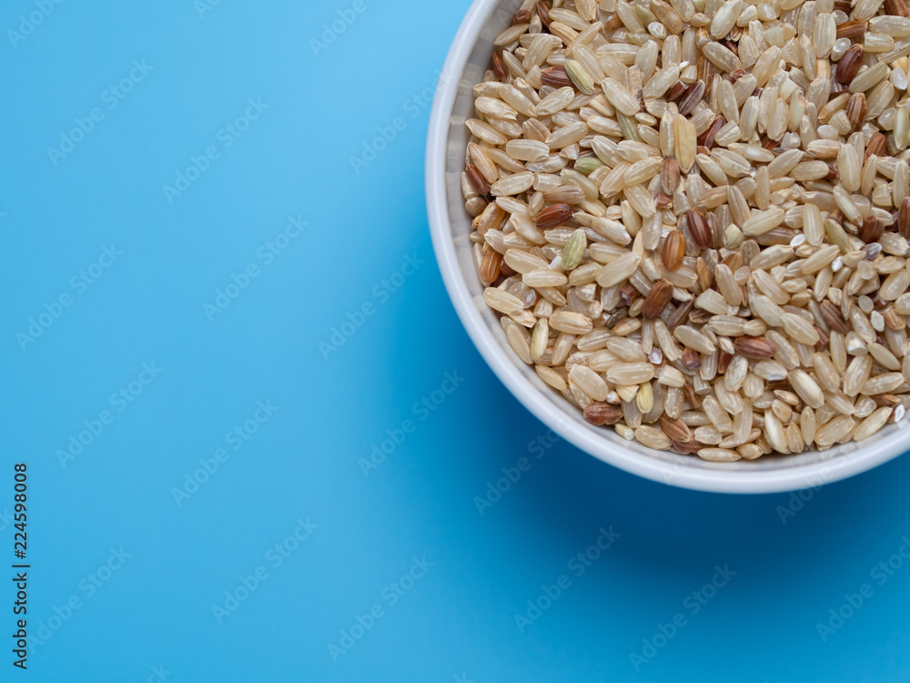 brown rice in white cup on a blue background brown rice in white cup on a blue background