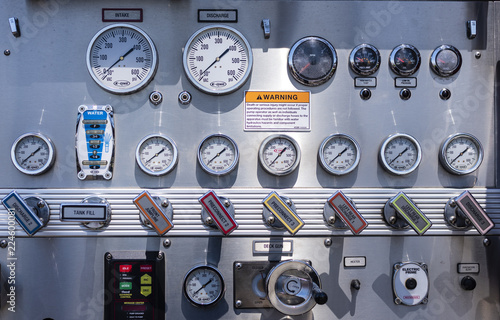 Complex control panel on a fire engine or fire truck with details on pump controls, knobs, gauges, and valves.