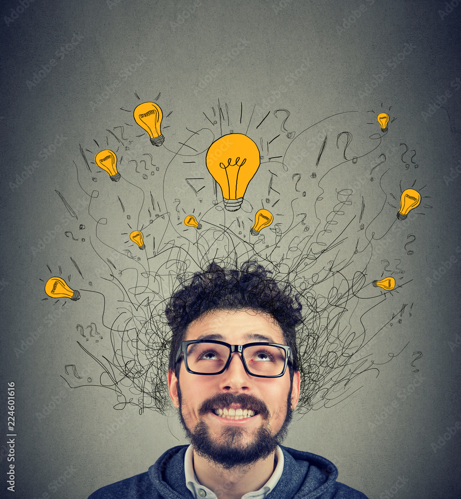 Excited man looking up at many ideas light bulbs above head Excited man looking up at many ideas light bulbs above head