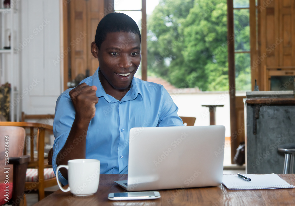 Cheering african american man with laptop Cheering african american man with laptop